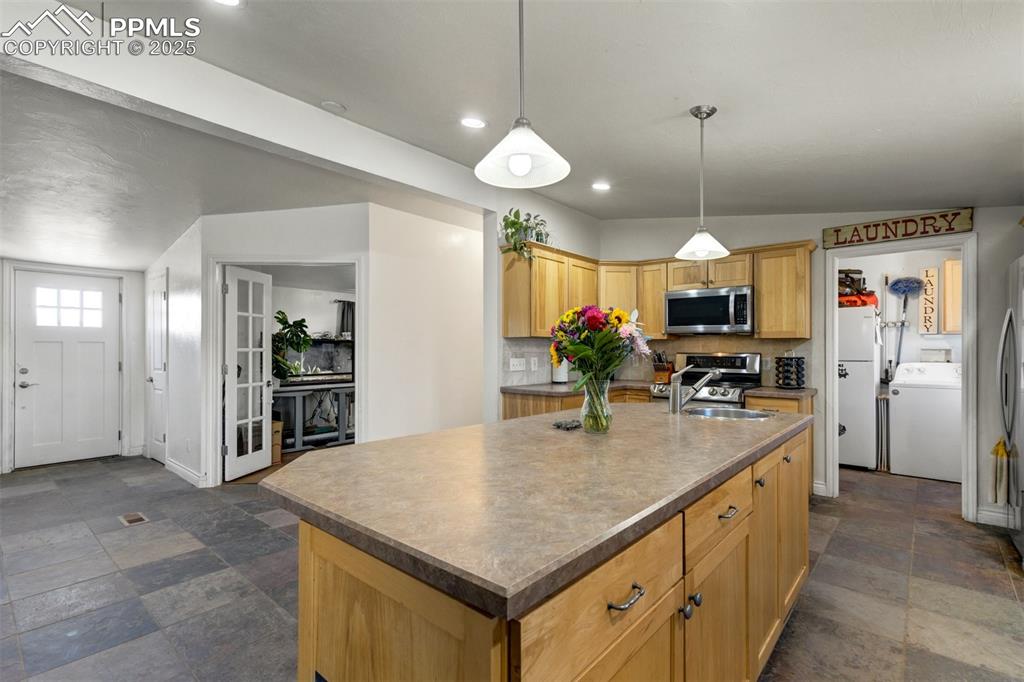 Image 9 of 50: Kitchen with washer / clothes dryer, stainless steel appliances, an island 