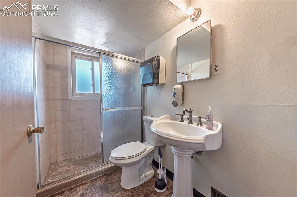 Image 13 of 31: bath featuring a stall shower, a textured wall, and a textured ceiling