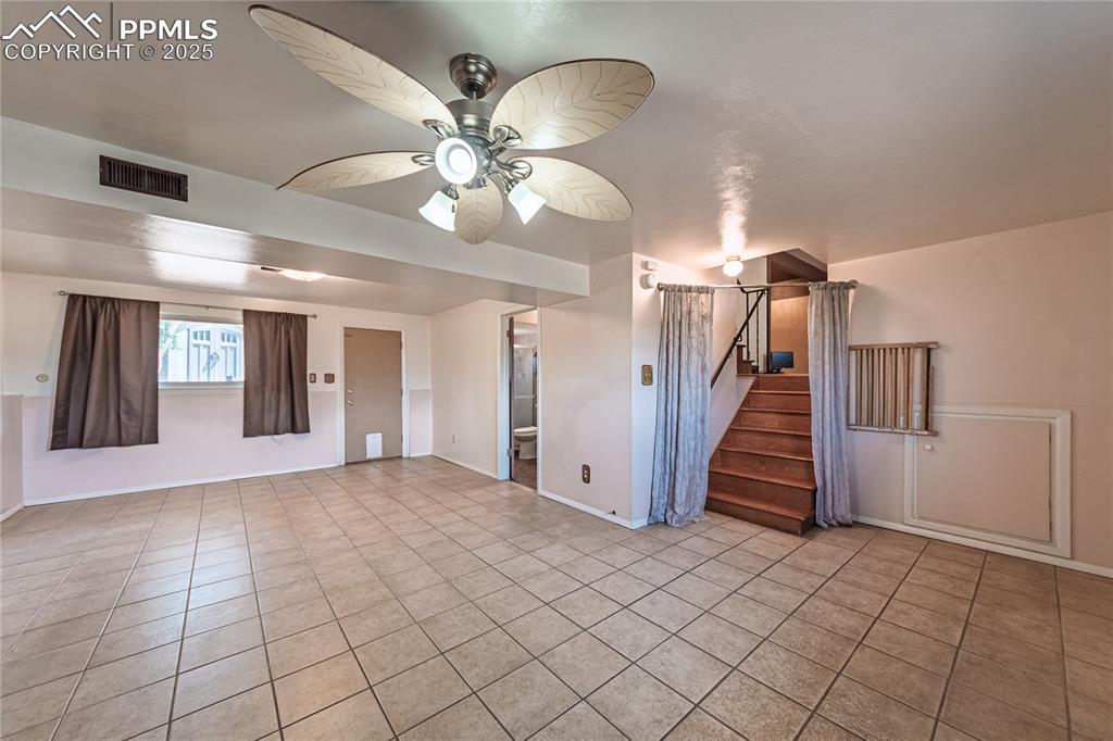 Image 15 of 31: living room with light tile patterned floors, stairway, and a ceiling fan