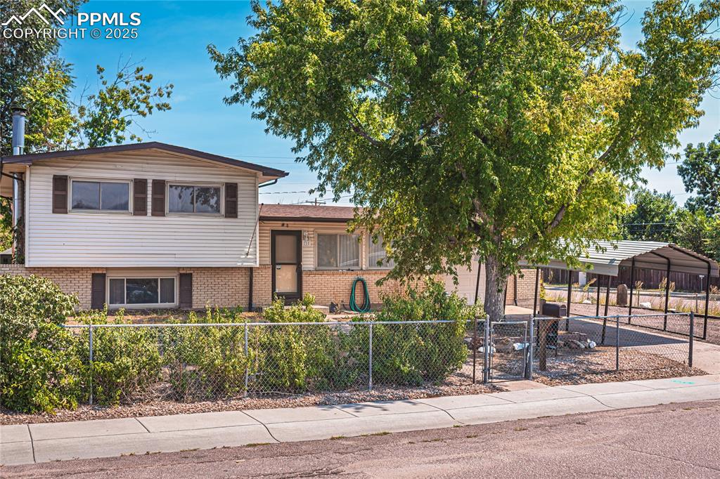 Image 2 of 31: Tri-level home with brick siding and a fenced front yard
