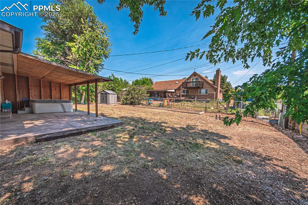 Image 27 of 31: Fenced backyard featuring a storage shed and a hot tub