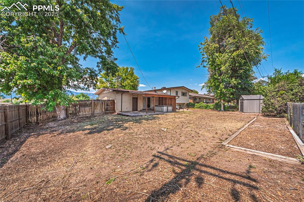 Image 29 of 31: Fenced backyard with a patio and a shed