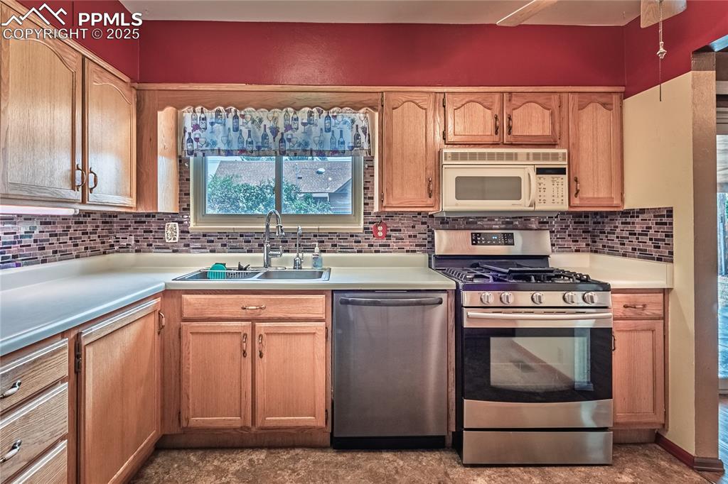 Image 3 of 31: Kitchen with appliances with stainless steel finishes, light countertops, d