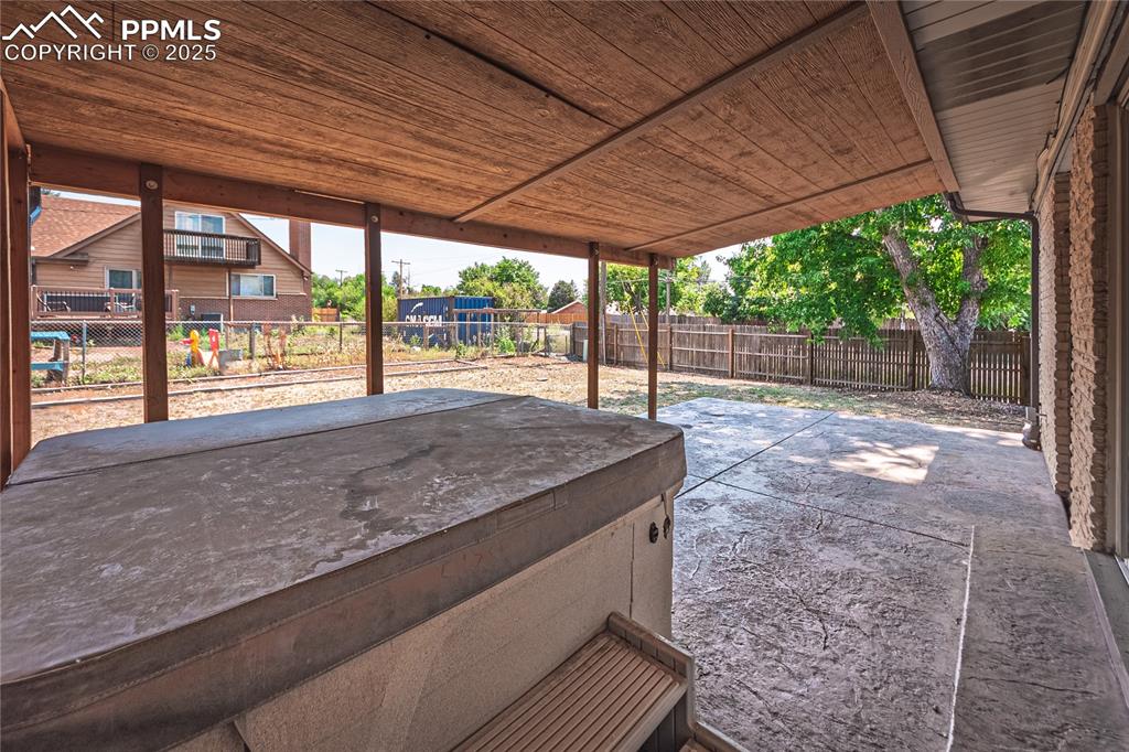 Image 30 of 31: Fenced backyard with a patio and a hot tub