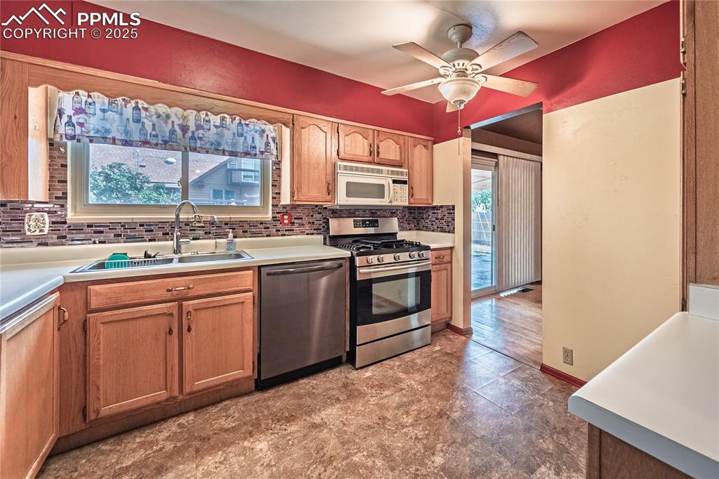 Image 4 of 31: Kitchen featuring stainless steel appliances, backsplash, light countertops