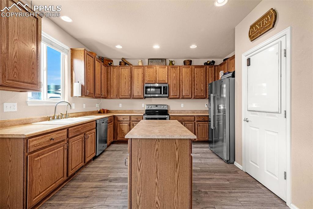 Image 10 of 40: Full kitchen featuring wood-finish cabinetry, a central island, recessed li