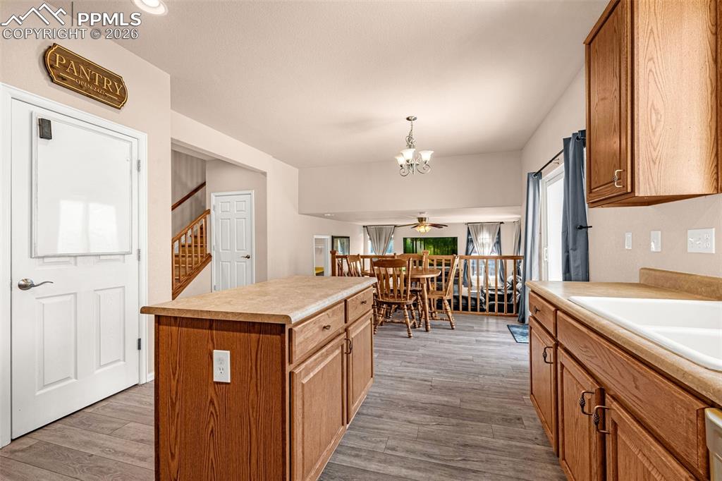 Image 11 of 40: Kitchen featuring a central island with wood-finish cabinetry and light-ton