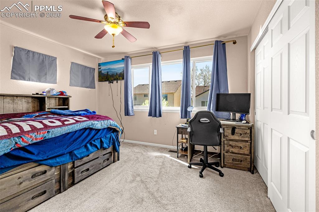 Image 14 of 40: Carpeted room featuring a ceiling fan with light, three windows, and a slid