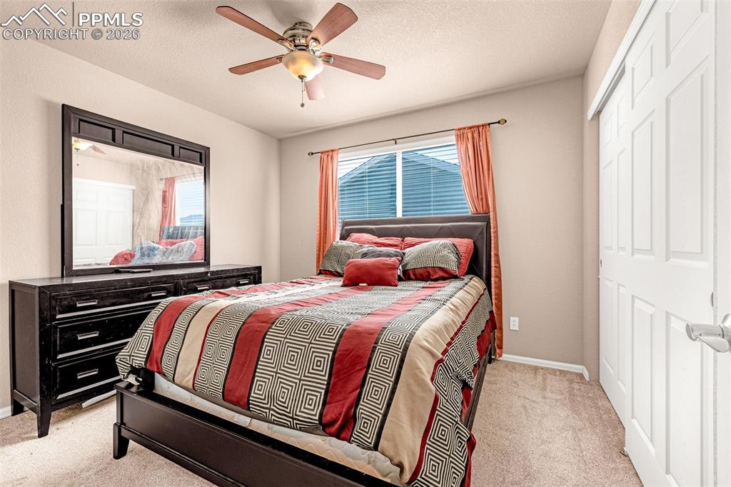 Image 15 of 40: Carpeted bedroom featuring a ceiling fan with integrated lighting, window w