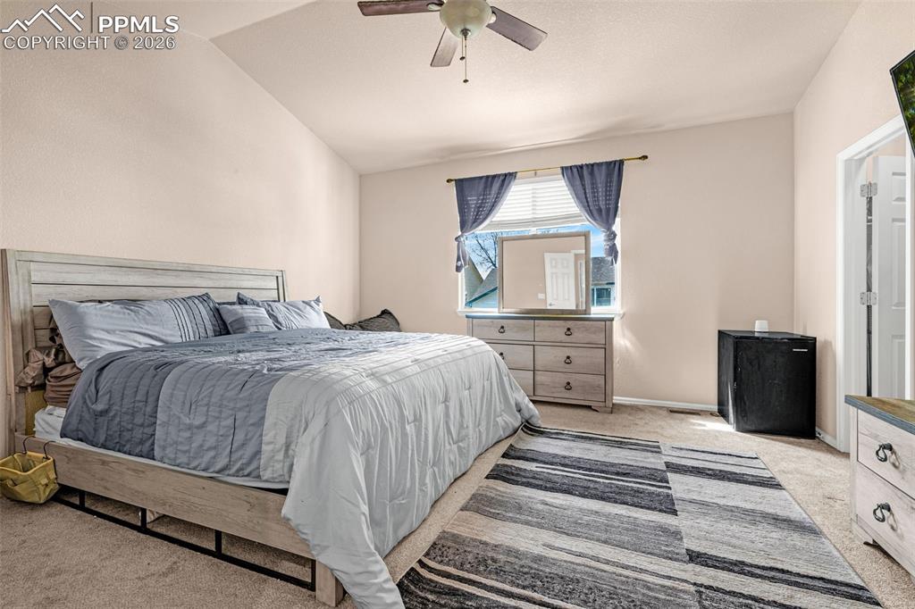 Image 17 of 40: Spacious bedroom featuring vaulted ceilings, ceiling fan, carpeted flooring