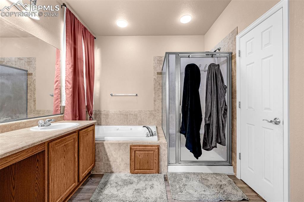 Image 22 of 40: Bathroom featuring a built-in jetted tub, glass-enclosed shower, wood-finis