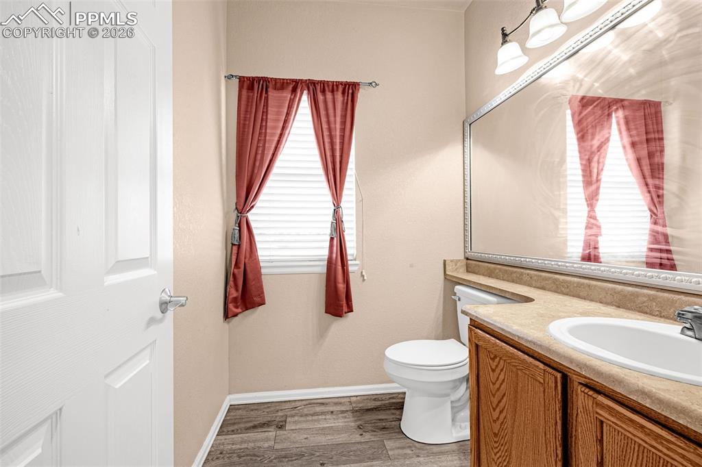 Image 24 of 40: Bathroom featuring wood-finish flooring, a single window with blinds, a whi