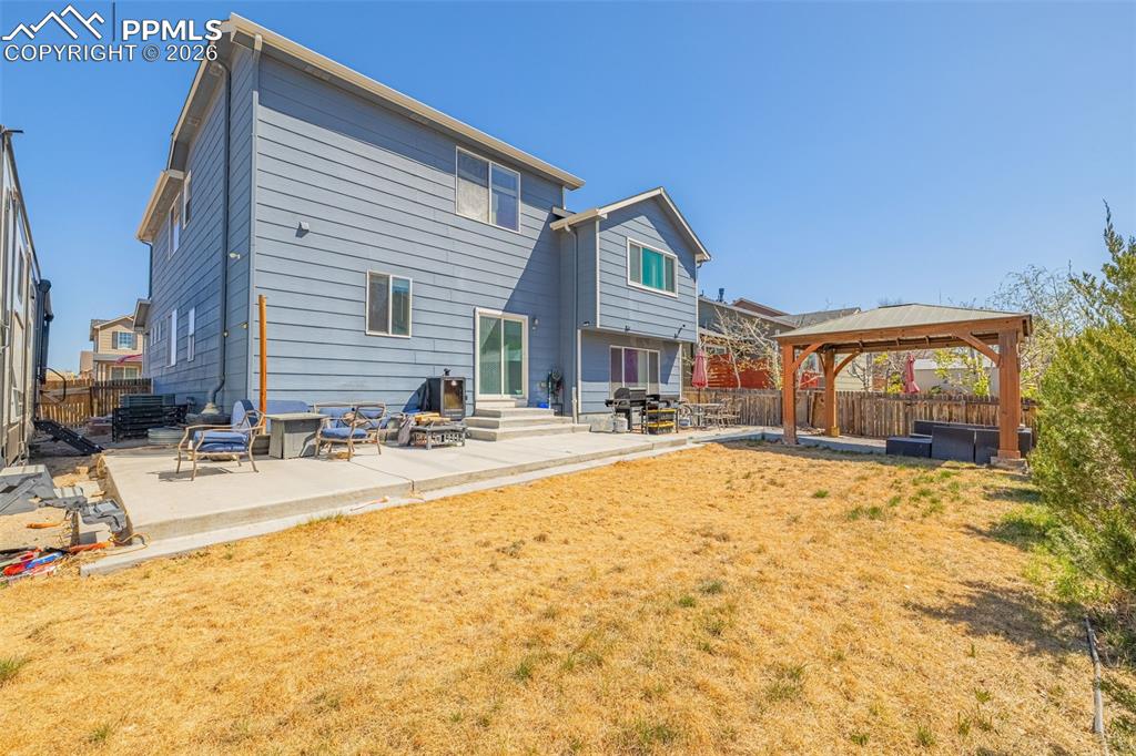 Image 31 of 40: Expansive backyard featuring a concrete patio, a detached wooden pergola, a