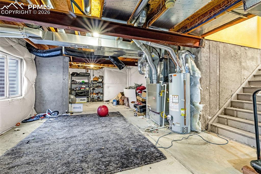 Image 33 of 40: Unfinished basement with concrete flooring and exposed structural beams