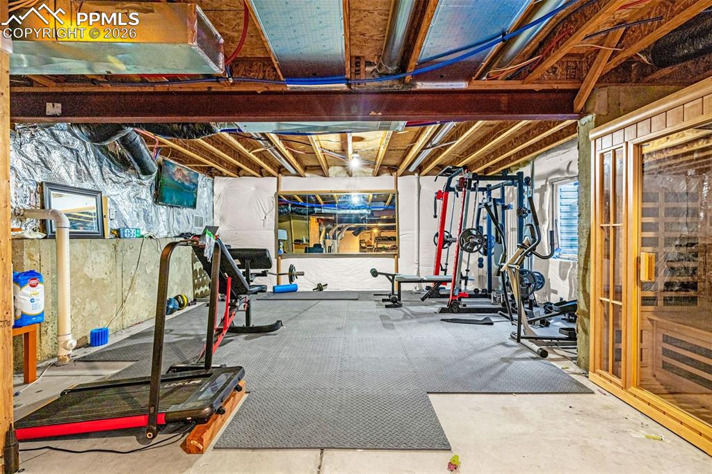 Image 34 of 40: Basement fitness area featuring concrete flooring, exposed ceiling joists,