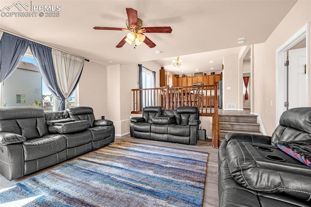 Image 7 of 40: Spacious living area featuring wood-finish flooring, a ceiling fan with int