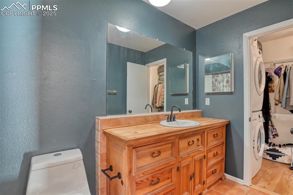 Image 19 of 31: Bathroom featuring a spacious closet, a textured wall, vanity, stacked wash