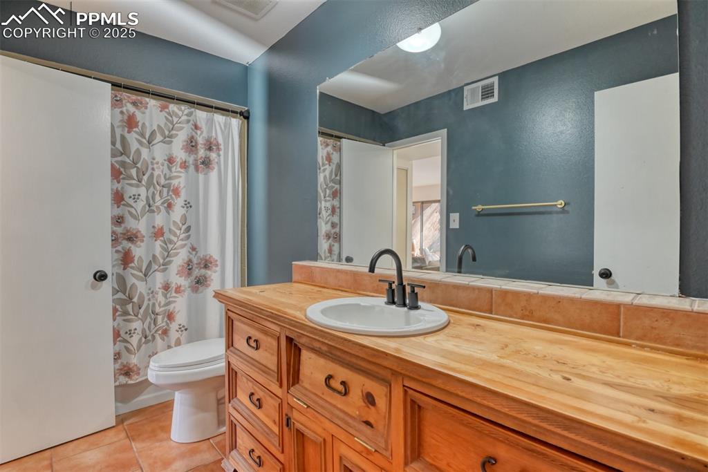 Image 20 of 31: Full bath with a shower with curtain, light tile patterned floors, and vani