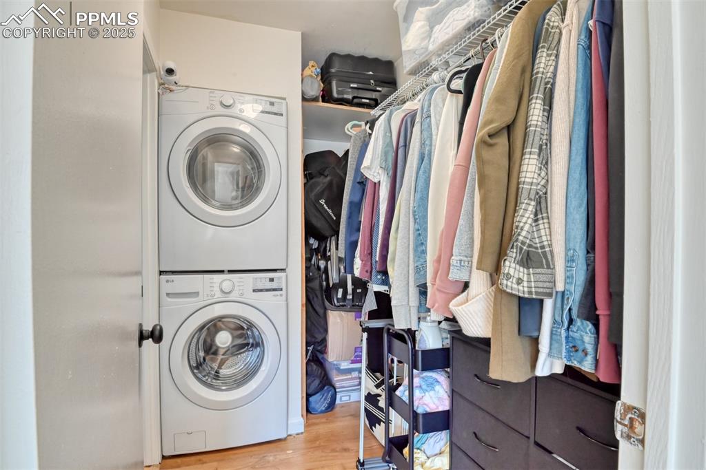 Image 21 of 31: Laundry area featuring stacked washer and clothes dryer and light wood-styl