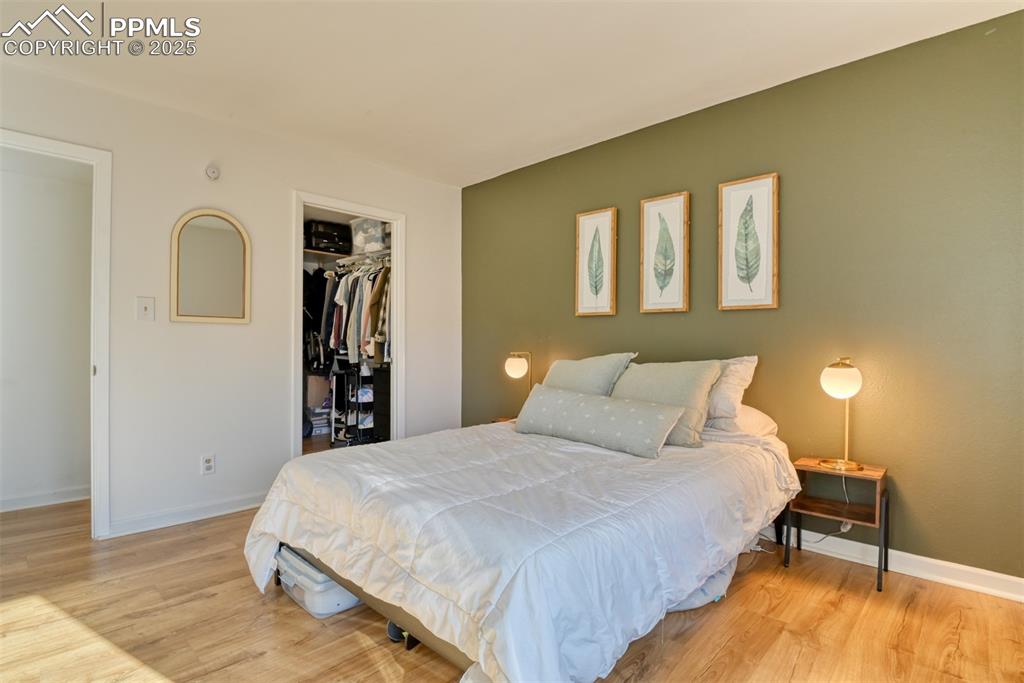 Image 24 of 31: Bedroom with a walk in closet and light wood finished floors