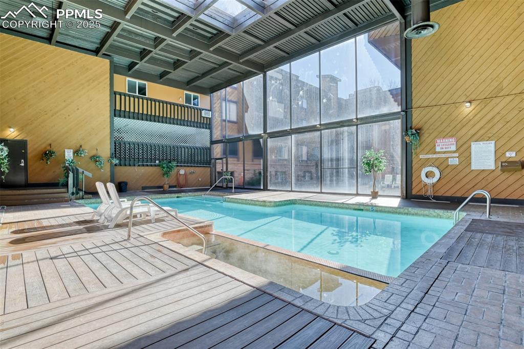 Image 29 of 31: Indoor community pool featuring a deck and a patio