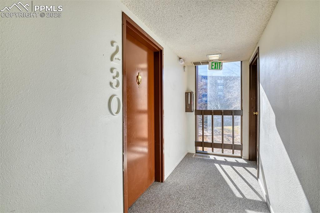 Image 4 of 31: Hallway with carpet, a textured ceiling, floor to ceiling windows, and a te