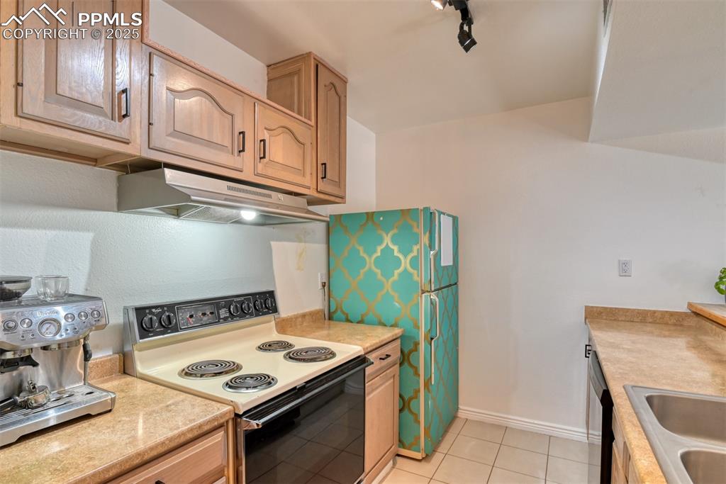 Image 5 of 31: Kitchen with electric stove, light countertops, under cabinet range hood, l