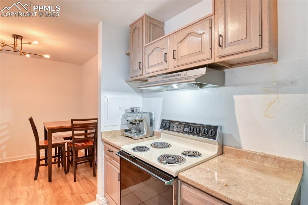 Image 7 of 31: Kitchen with electric stove, light countertops, under cabinet range hood, a