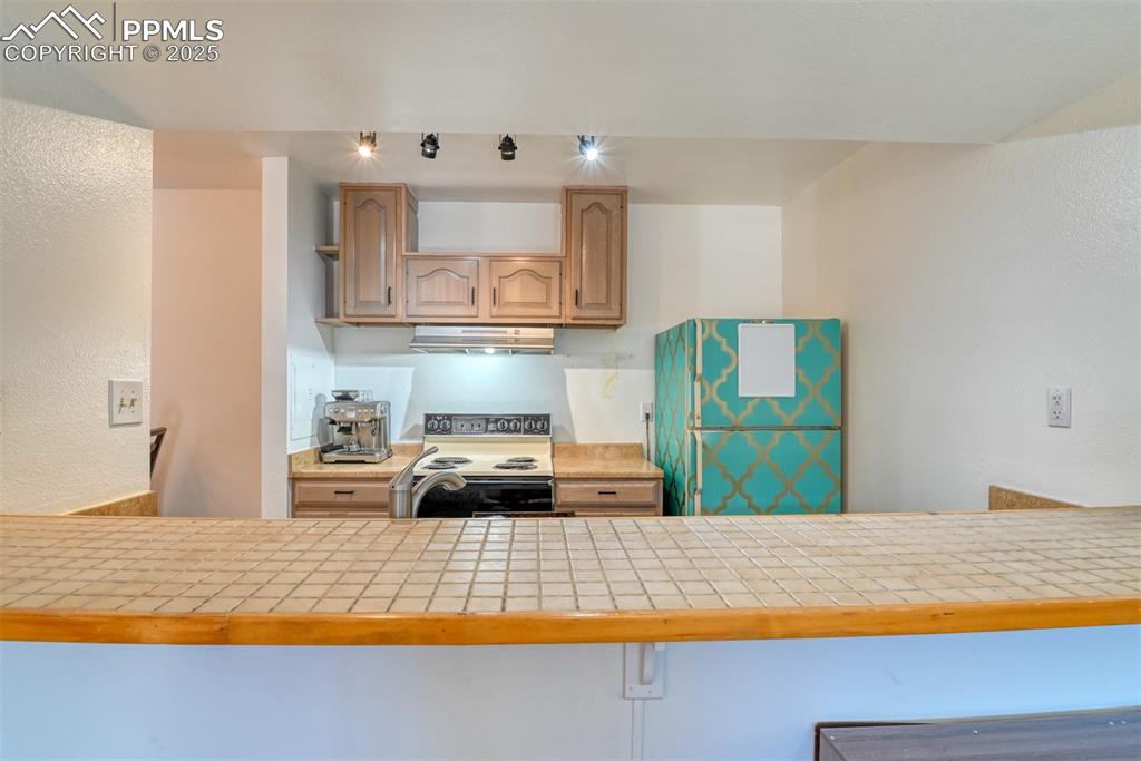 Image 9 of 31: Kitchen featuring range with electric stovetop, freestanding refrigerator,