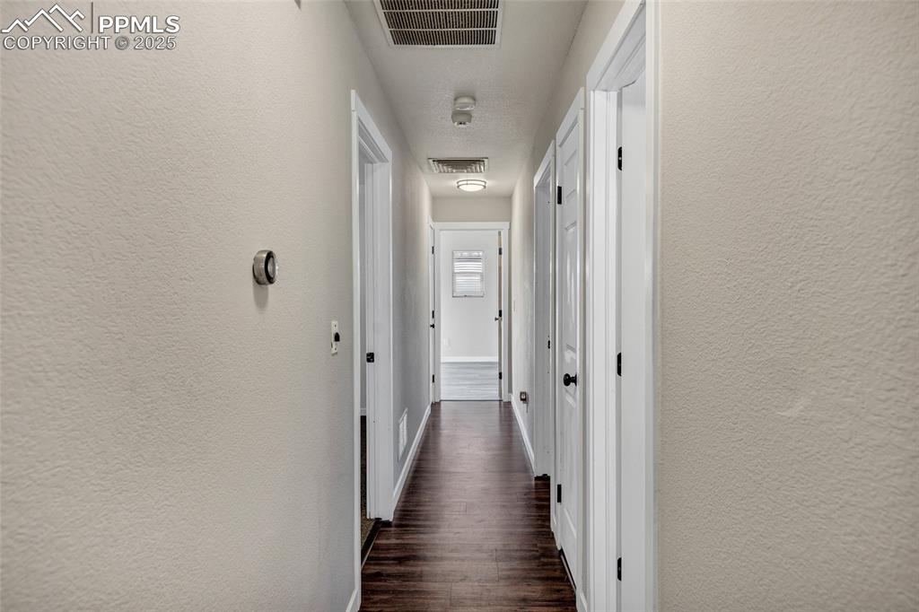 Image 11 of 22: Hallway with a textured wall and dark wood finished floors