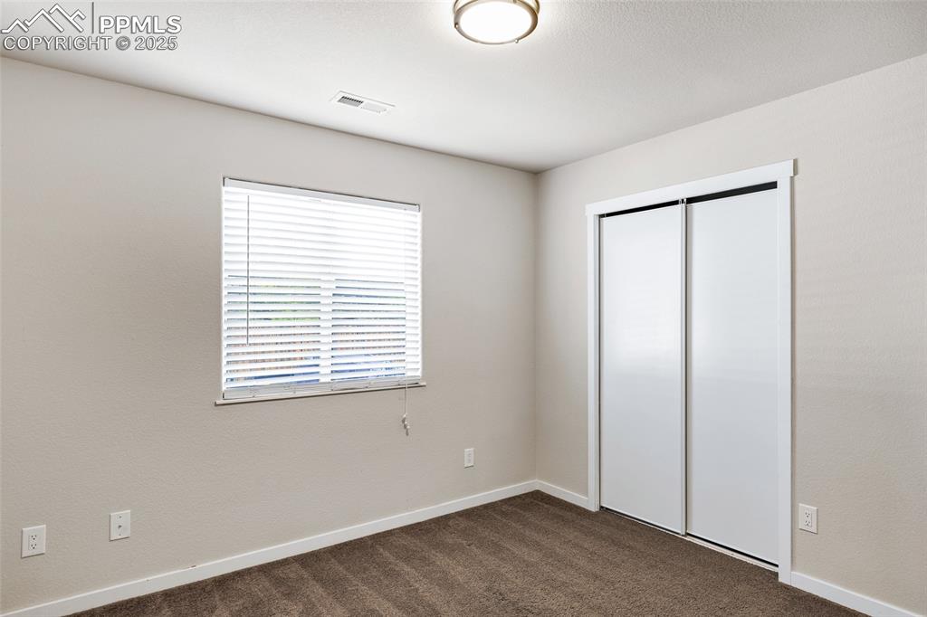 Image 13 of 22: Unfurnished bedroom featuring dark colored carpet and a closet