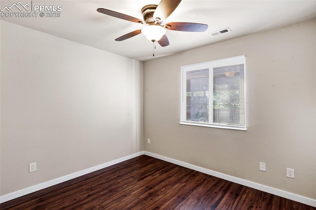 Image 14 of 22: Empty room with dark wood-style flooring and a ceiling fan