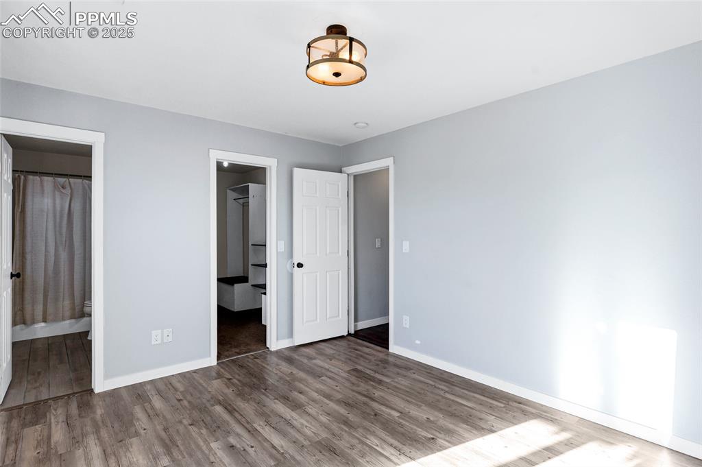 Image 16 of 22: Unfurnished bedroom featuring a spacious closet, wood finished floors, and