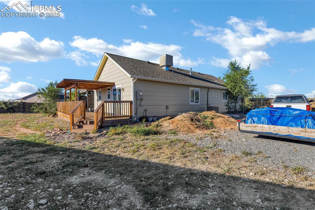 Image 19 of 22: View of side of home featuring a wooden deck and a cooling unit
