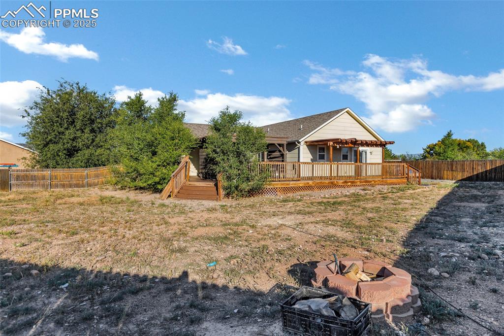Image 21 of 22: Rear view of house with a fenced backyard, a fire pit, and a deck