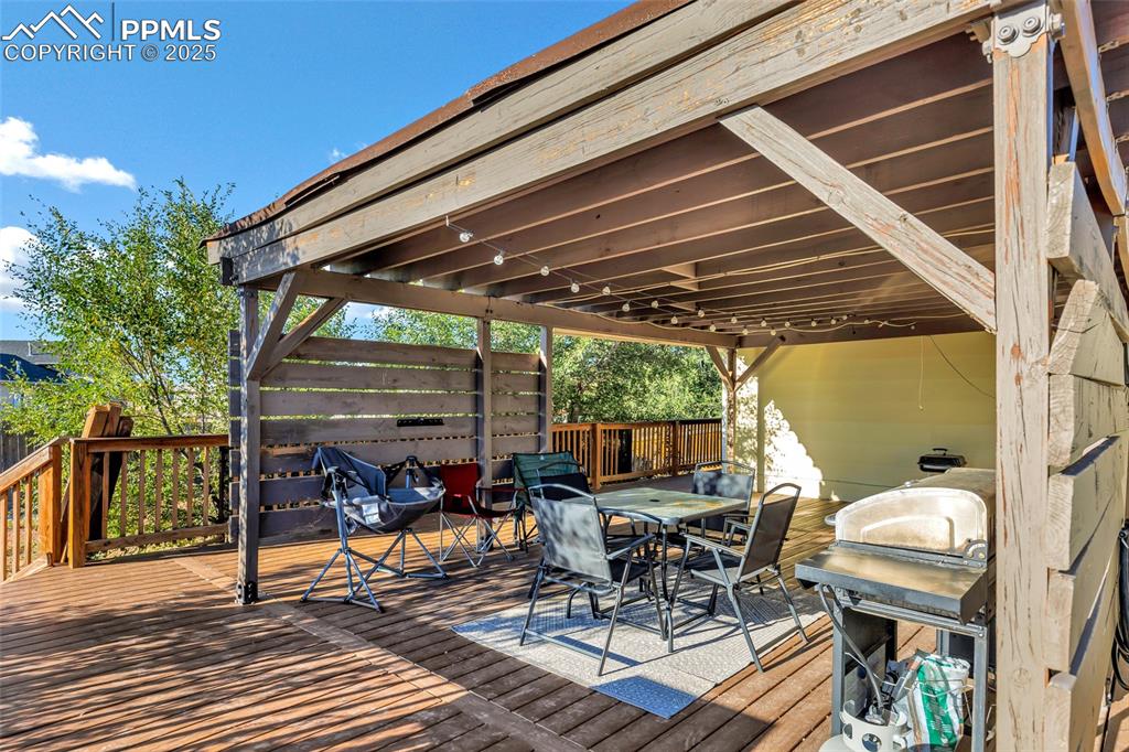 Image 22 of 22: Wooden deck featuring outdoor dining area and a grill