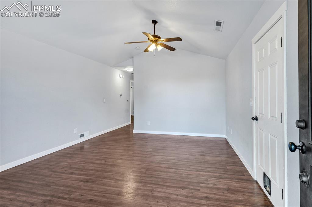 Image 4 of 22: Spare room with lofted ceiling, dark wood-style floors, and a ceiling fan