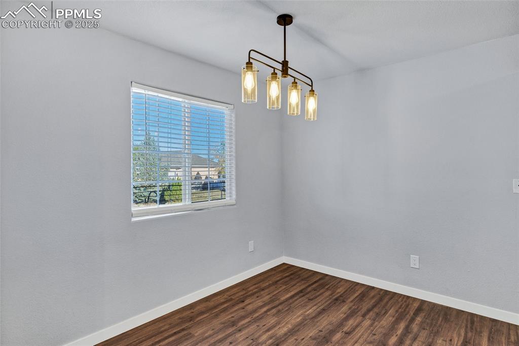 Image 6 of 22: Unfurnished room with baseboards and dark wood-type flooring
