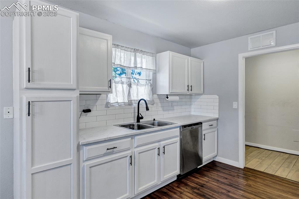 Image 8 of 22: Kitchen featuring white cabinets, decorative backsplash, dark wood-style fl