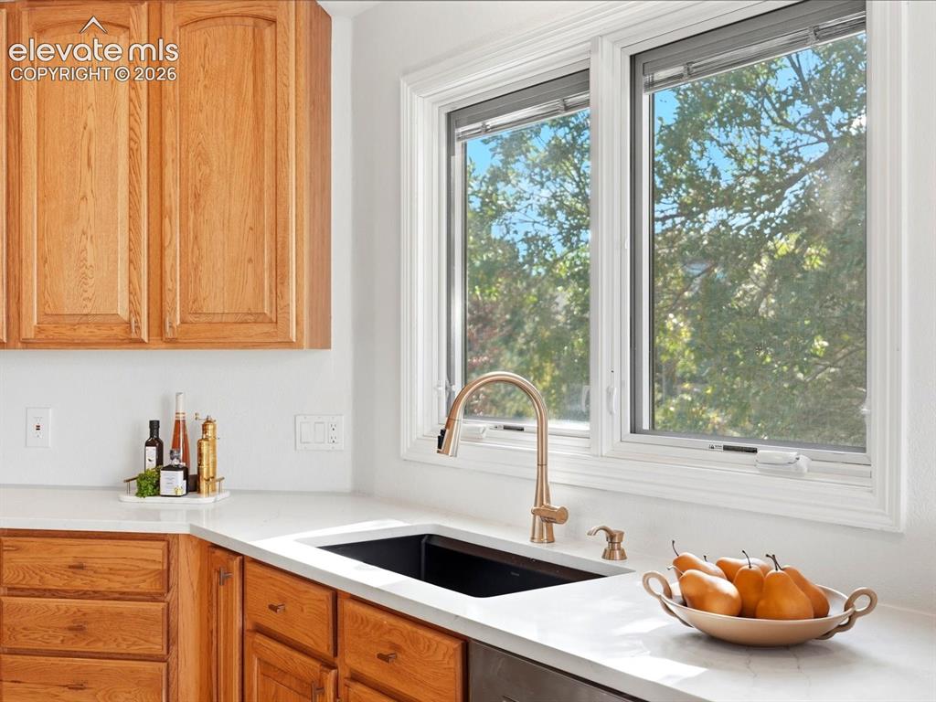Image 10 of 48: Natural wood-finish cabinetry, white solid-surface countertops, undermount