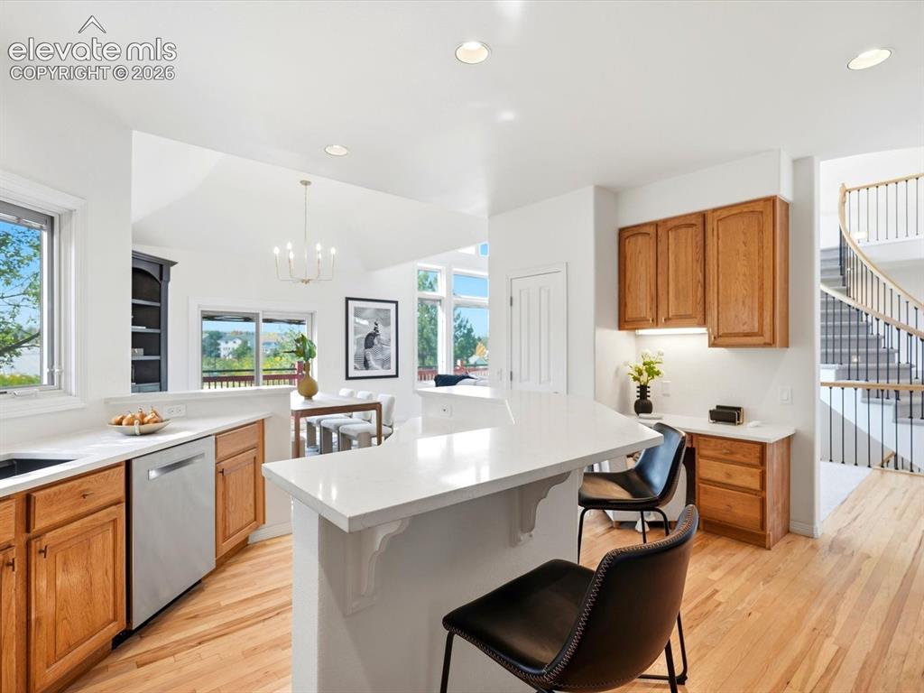 Image 12 of 48: Kitchen featuring a peninsula with solid-surface countertops, light wood ca