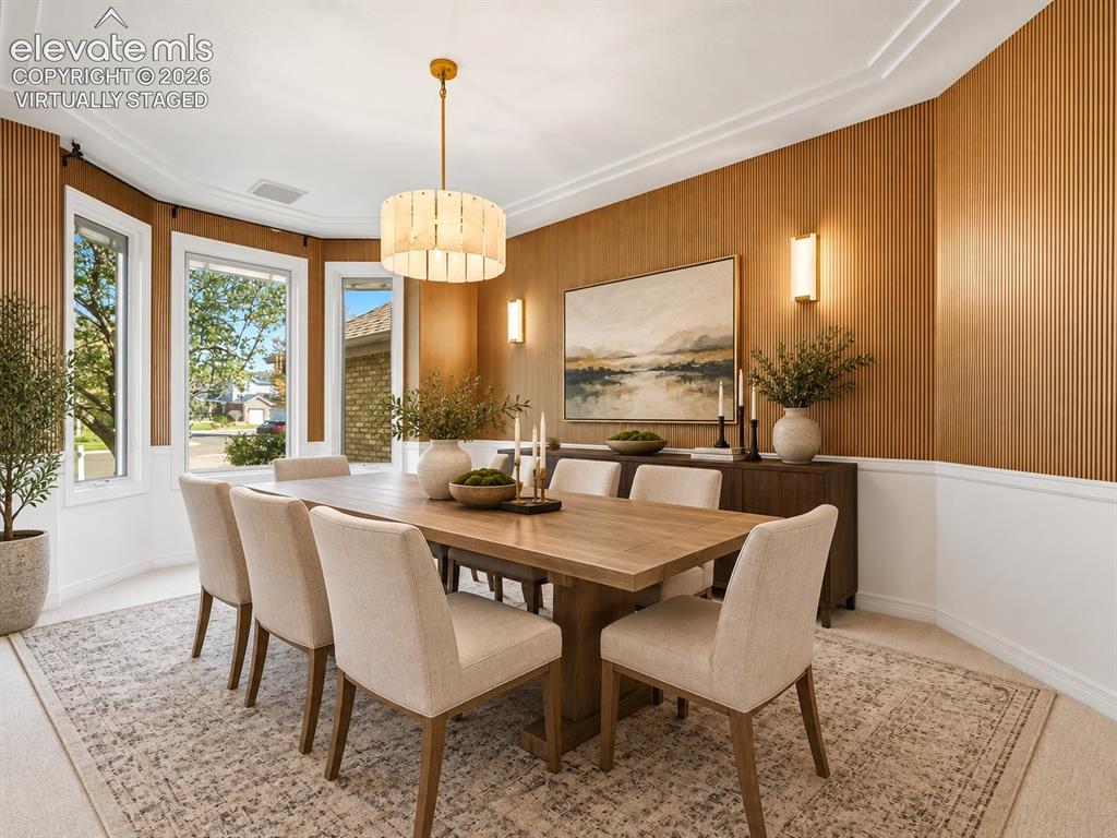 Image 16 of 48: Dining area featuring vertical wood-slat wall paneling, crown molding, a ba