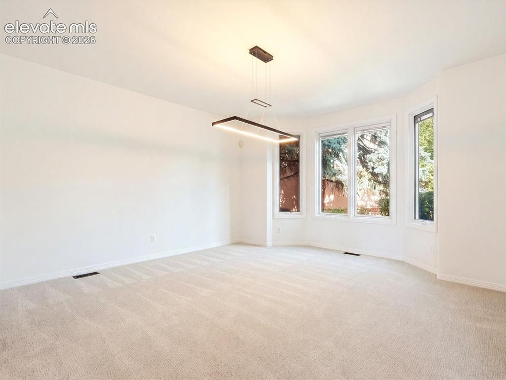 Image 19 of 48: Spacious room featuring a geometric, modern pendant light fixture, wall-to-