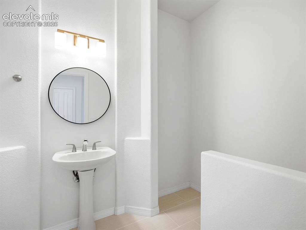 Image 20 of 48: Pedestal sink with a polished metal faucet, round wall-mounted mirror, and