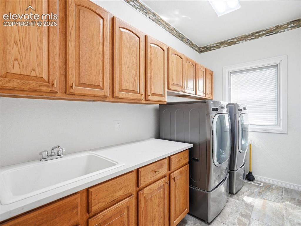 Image 23 of 48: Laundry space featuring wood-finish cabinetry, solid-surface countertop, in