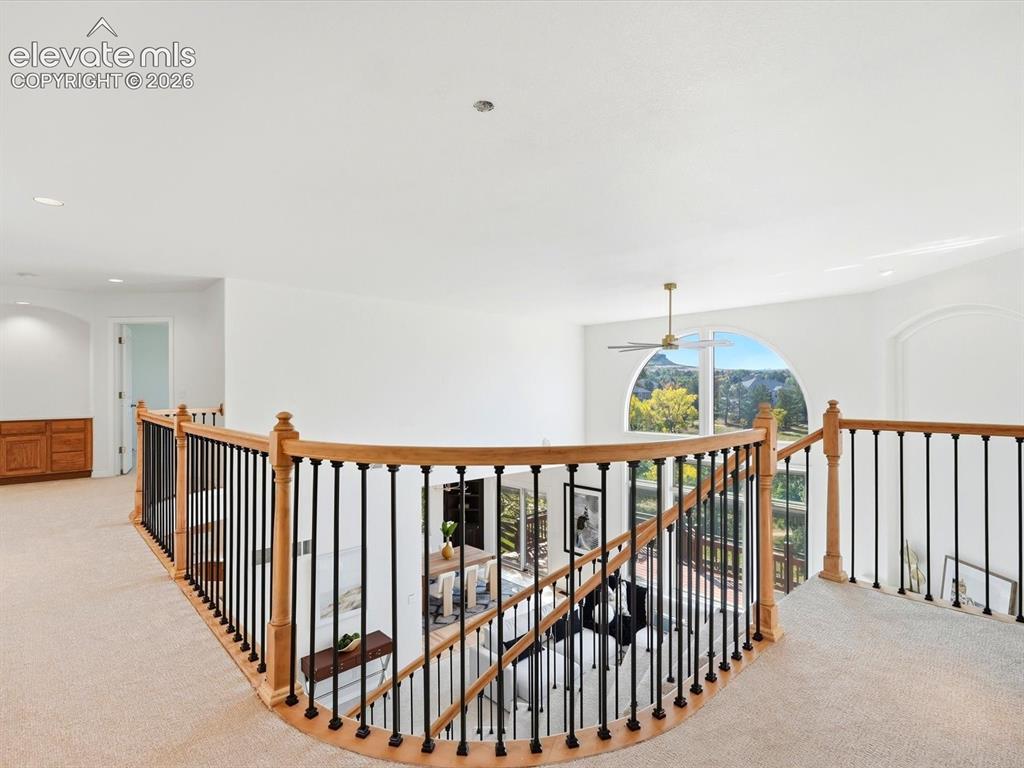 Image 24 of 48: Curved landing featuring a light wood railing with black metal balusters an