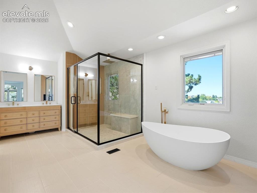 Image 29 of 48: Freestanding soaking tub with floor-mounted brass faucet, walk-in glass-enc