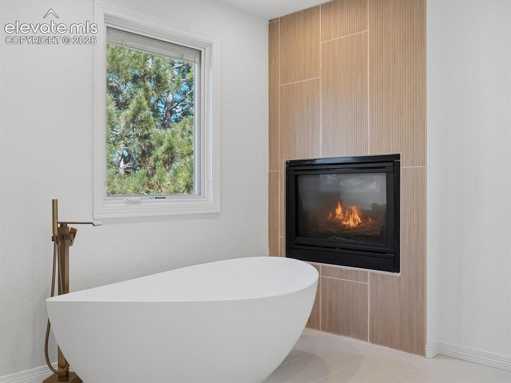 Image 30 of 48: Freestanding soaking tub with a floor-mounted bronze-finish faucet, built-i