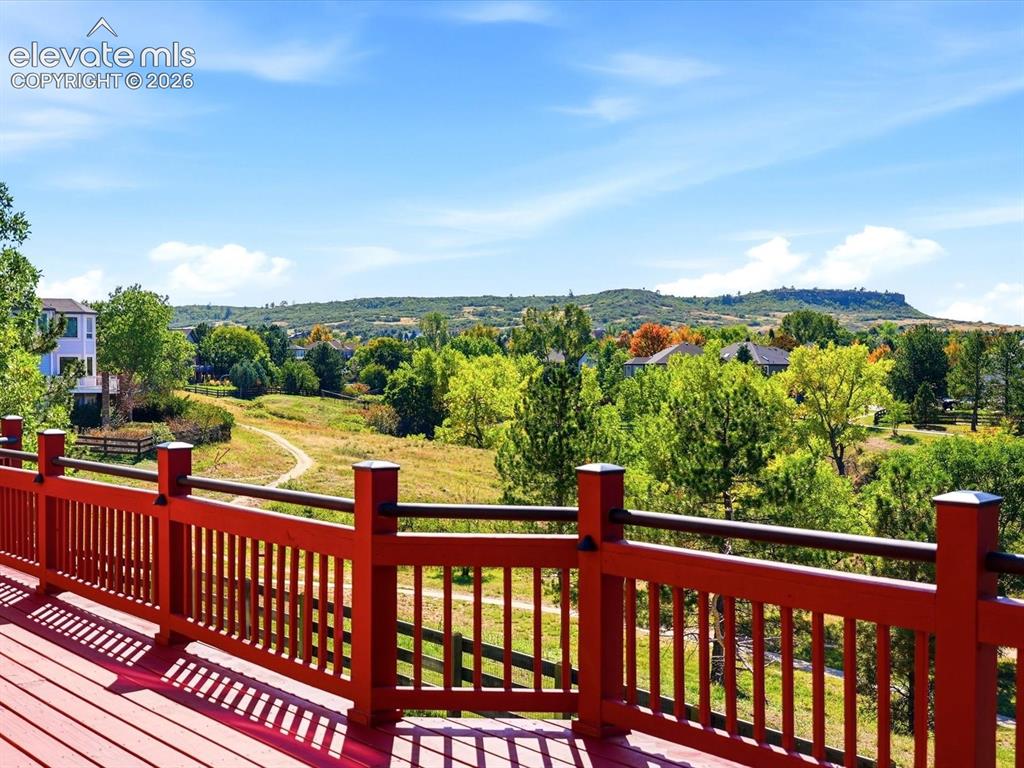 Image 46 of 48: Elevated deck with a red-painted wood railing, featuring an expansive lands