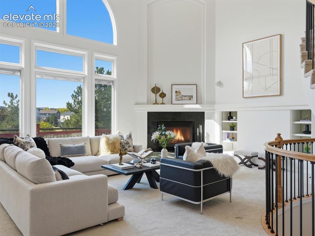 Image 5 of 48: High-ceilinged living area featuring a fireplace with a dark stone surround